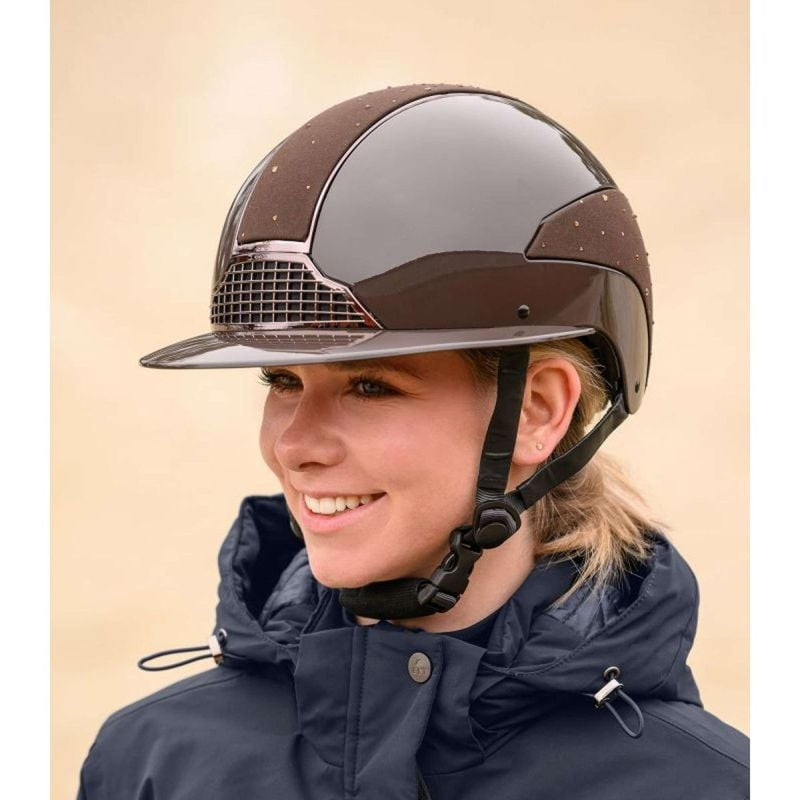 Femme portant le casque d'équitation SWING H24 Lady Spark marron en extérieur, vue de face souriante